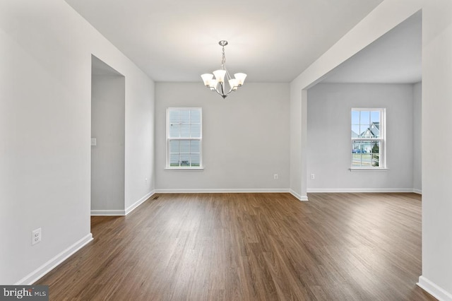 unfurnished room featuring dark wood-type flooring and an inviting chandelier