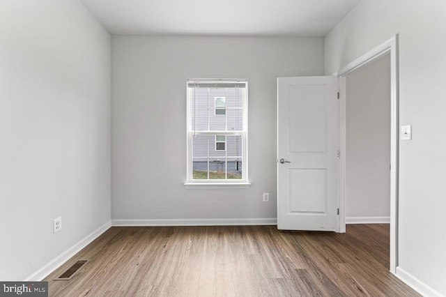 spare room with plenty of natural light and hardwood / wood-style floors