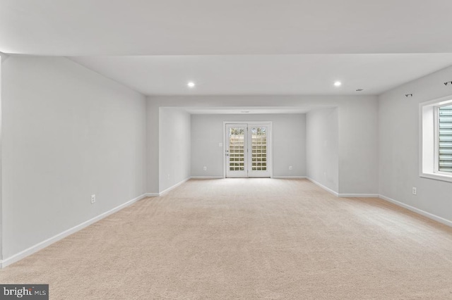 empty room featuring a healthy amount of sunlight, light carpet, and french doors