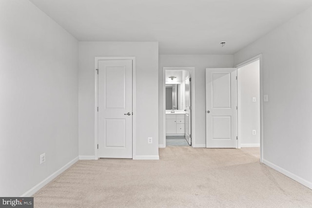 unfurnished bedroom featuring sink, ensuite bath, and light colored carpet