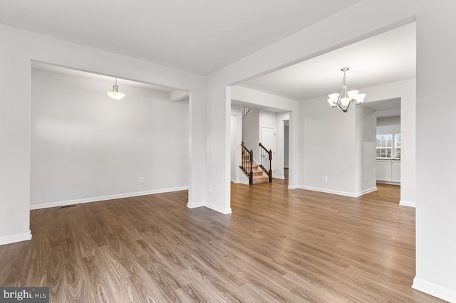 unfurnished living room featuring wood-type flooring and a chandelier