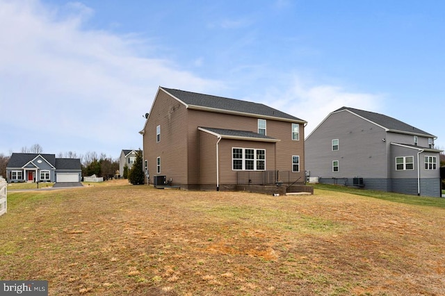 rear view of house featuring cooling unit and a lawn