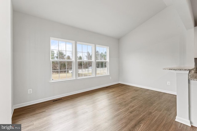 unfurnished living room featuring vaulted ceiling and dark hardwood / wood-style flooring