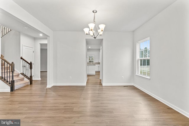 unfurnished dining area with light hardwood / wood-style flooring and a notable chandelier