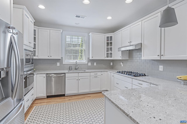 kitchen with a sink, stainless steel appliances, white cabinetry, and under cabinet range hood