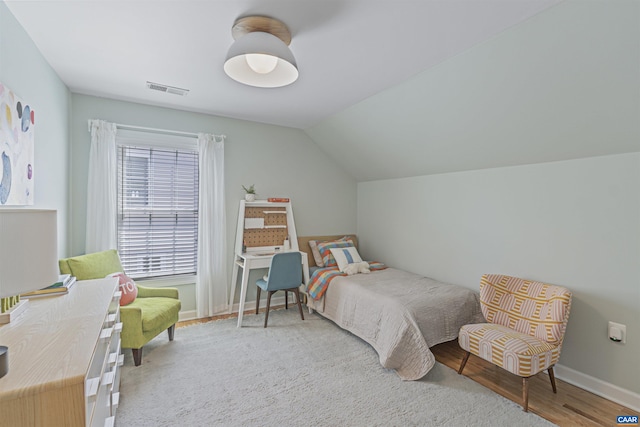 bedroom with baseboards, visible vents, wood finished floors, and lofted ceiling