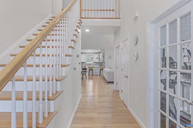 interior space featuring baseboards, a high ceiling, wood finished floors, and stairway