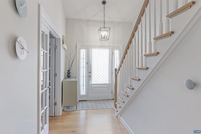 foyer with an inviting chandelier, stairs, and wood finished floors