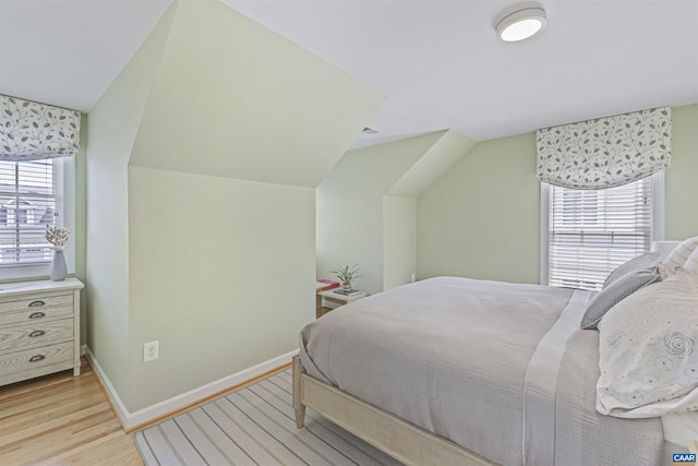 bedroom with light wood-style floors, baseboards, and vaulted ceiling