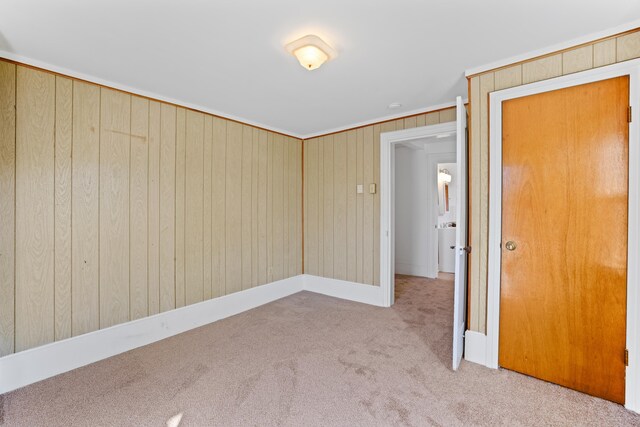 unfurnished room with light colored carpet and wood walls