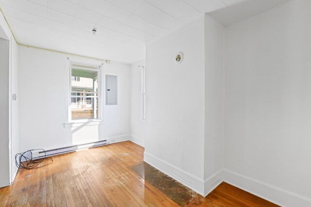 unfurnished room featuring hardwood / wood-style flooring, a baseboard radiator, and electric panel