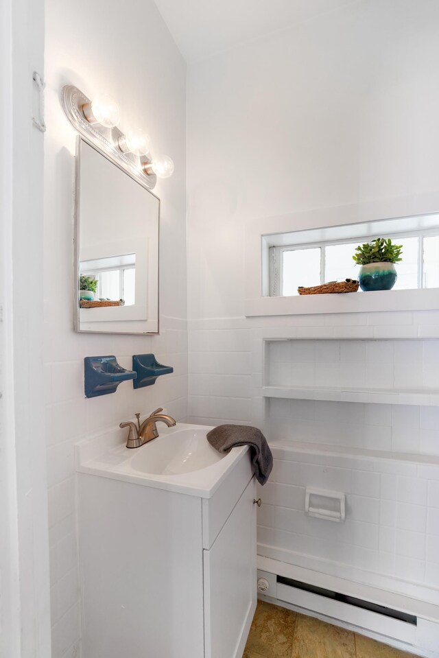 bathroom featuring a healthy amount of sunlight, vanity, tile walls, and a baseboard heating unit