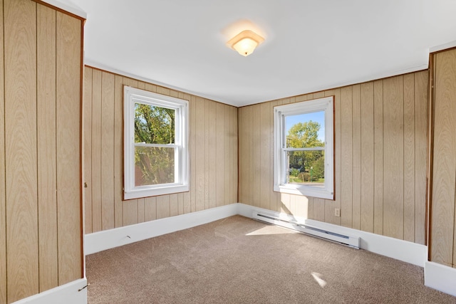 carpeted empty room featuring a baseboard radiator, a healthy amount of sunlight, and wooden walls