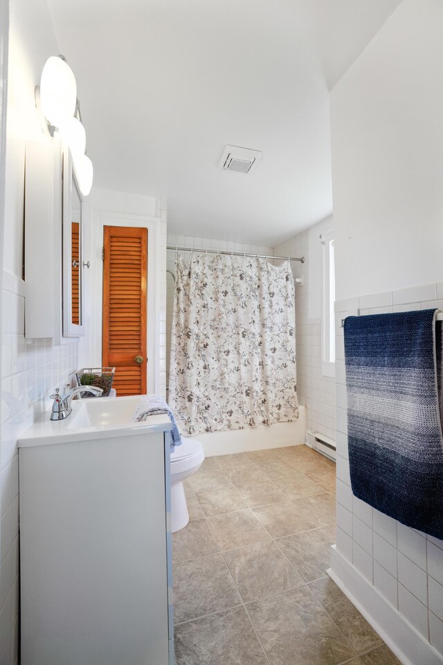 full bathroom featuring shower / tub combo with curtain, toilet, tile walls, baseboard heating, and vanity