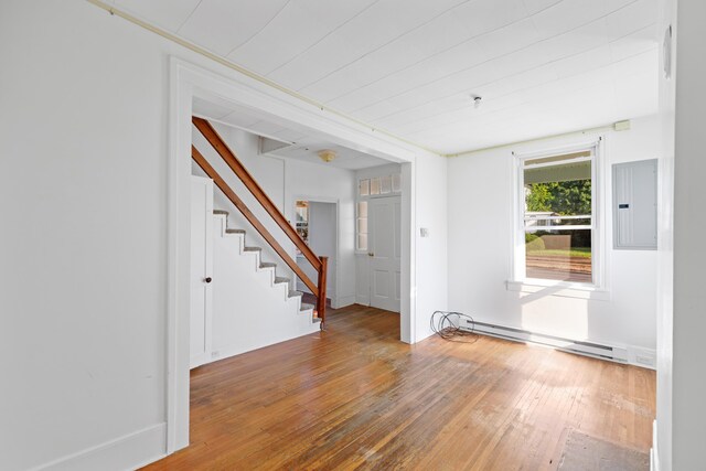 unfurnished room featuring baseboard heating, electric panel, and hardwood / wood-style floors