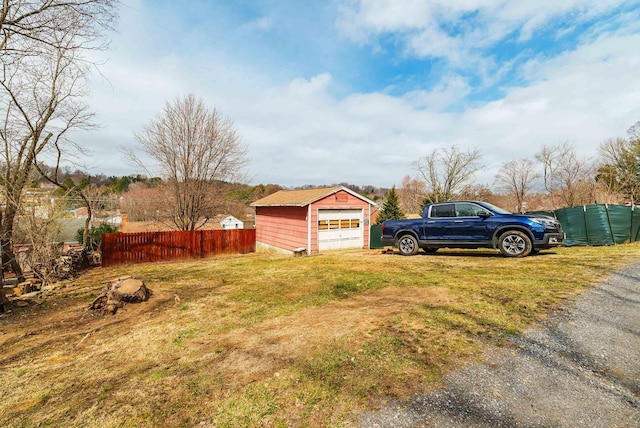 view of yard featuring an outbuilding, a detached garage, and fence