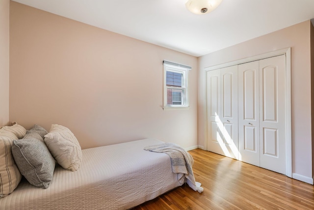 bedroom featuring wood finished floors, a closet, and baseboards