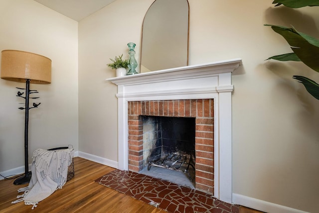 room details featuring a brick fireplace, baseboards, and wood finished floors