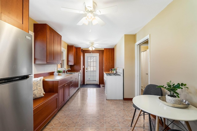 kitchen featuring washer / clothes dryer, freestanding refrigerator, ceiling fan, a sink, and light countertops