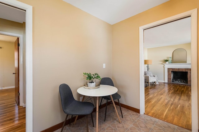 dining area featuring a fireplace, baseboards, and wood finished floors