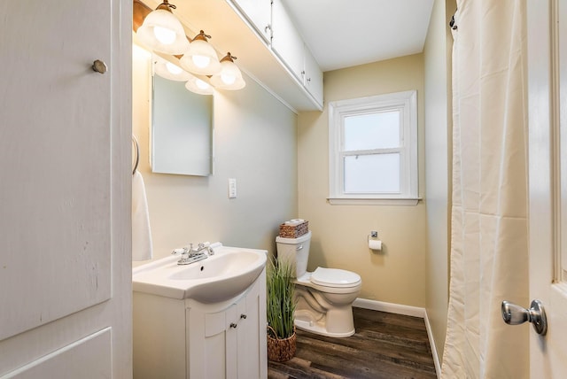 bathroom featuring baseboards, toilet, wood finished floors, and vanity