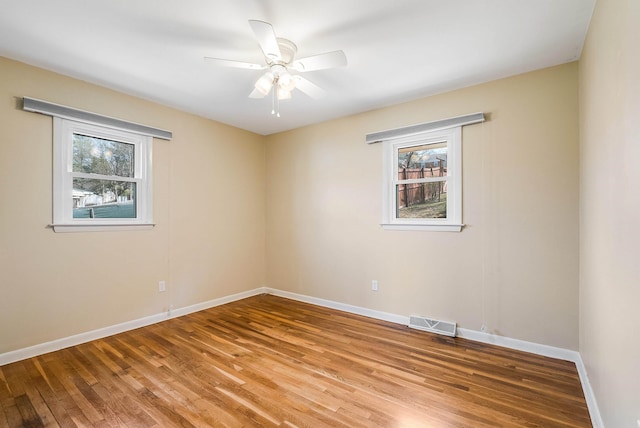 unfurnished room featuring visible vents, baseboards, wood finished floors, and a ceiling fan