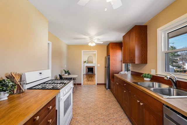 kitchen featuring a sink, stainless steel appliances, ceiling fan, and butcher block counters