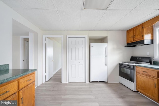 kitchen with white fridge, a paneled ceiling, range with gas stovetop, and light hardwood / wood-style flooring