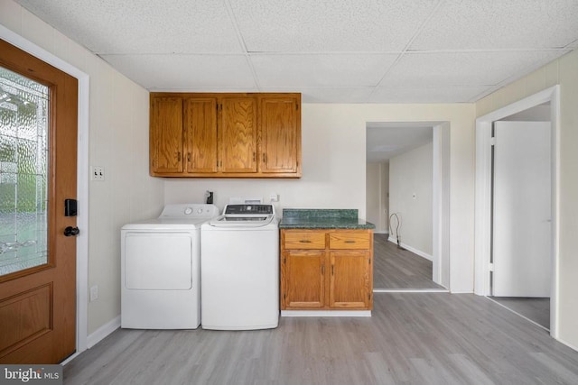 washroom with separate washer and dryer, light hardwood / wood-style floors, and cabinets