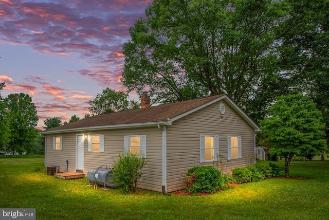 property exterior at dusk featuring a yard and central air condition unit