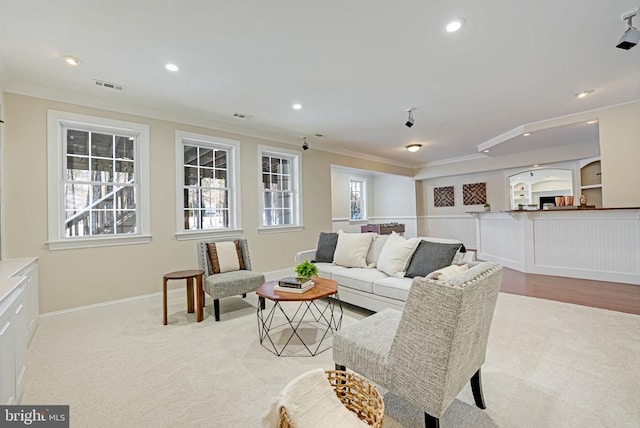 living room with recessed lighting, visible vents, a wealth of natural light, and ornamental molding