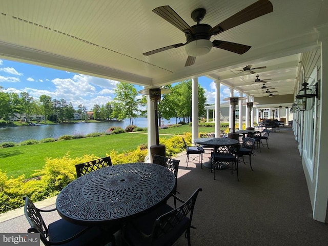 view of patio featuring outdoor dining area, a water view, and a ceiling fan