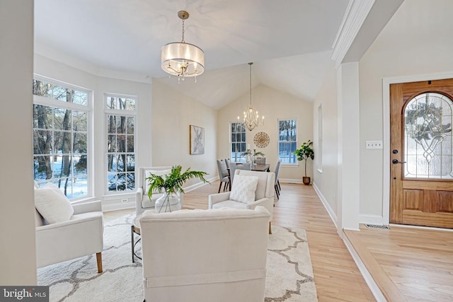 entryway with visible vents, baseboards, vaulted ceiling, light wood finished floors, and an inviting chandelier