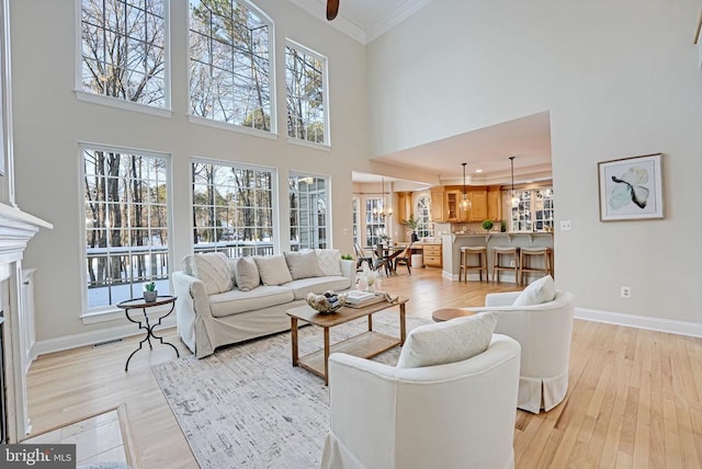 living area with light wood-style floors, baseboards, crown molding, and a glass covered fireplace