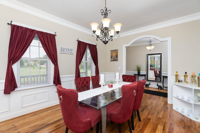 dining room featuring an inviting chandelier, arched walkways, ornamental molding, and plenty of natural light