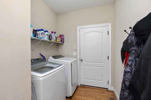 clothes washing area with washer and dryer, laundry area, and light wood finished floors