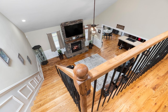 stairs featuring ceiling fan, a fireplace, a decorative wall, and wood finished floors