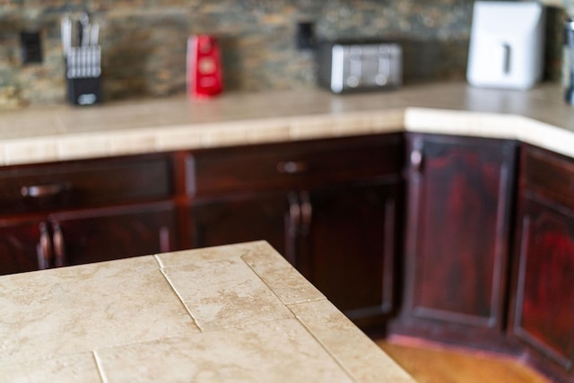 room details featuring light countertops, tasteful backsplash, and reddish brown cabinets