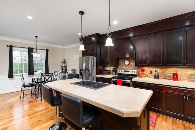 kitchen with premium range hood, light countertops, a sink, light wood finished floors, and appliances with stainless steel finishes