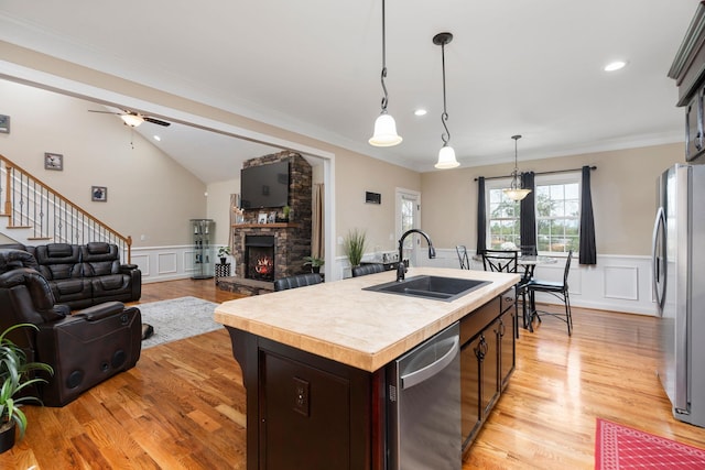 kitchen with appliances with stainless steel finishes, a sink, light countertops, open floor plan, and a decorative wall