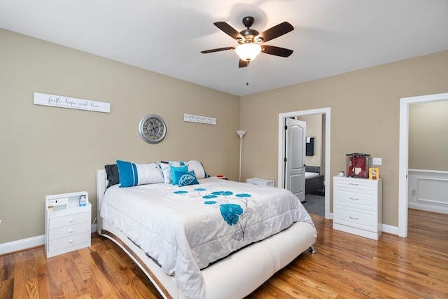 bedroom with baseboards, a ceiling fan, ensuite bath, and wood finished floors