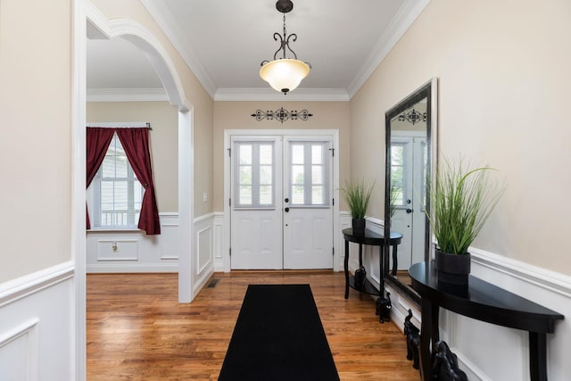 foyer featuring crown molding, wood finished floors, and a wainscoted wall