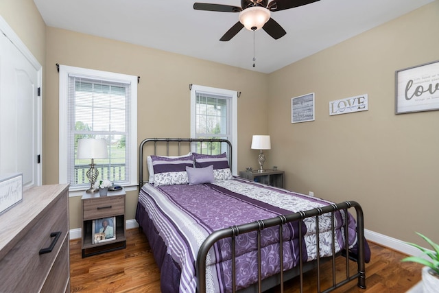 bedroom featuring a ceiling fan, baseboards, multiple windows, and wood finished floors
