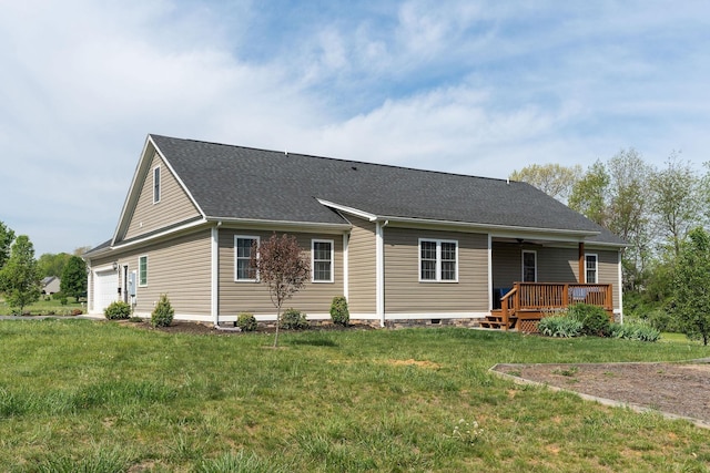 rear view of house with a shingled roof, a garage, ceiling fan, a deck, and a yard
