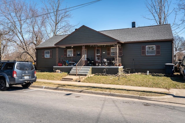 view of front of home featuring a porch, a chimney, and a shingled roof