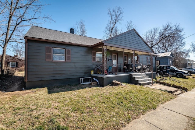 bungalow with covered porch, a chimney, a front yard, and roof with shingles