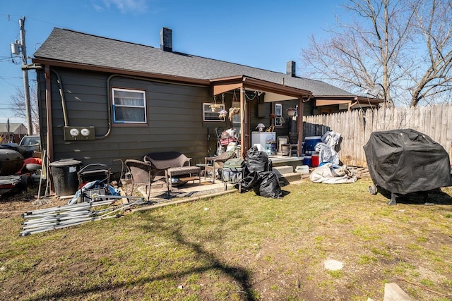 back of house featuring a yard, a patio, a shingled roof, and fence