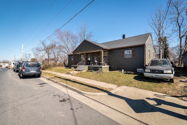 view of front of home featuring a porch, a front lawn, and a shingled roof