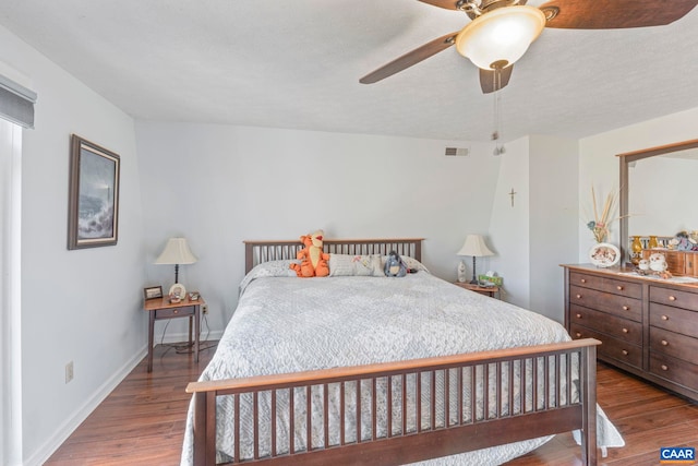 bedroom with dark wood-style floors, a ceiling fan, visible vents, and baseboards