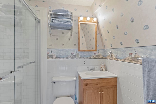 full bathroom featuring toilet, tile walls, wainscoting, a shower stall, and wallpapered walls